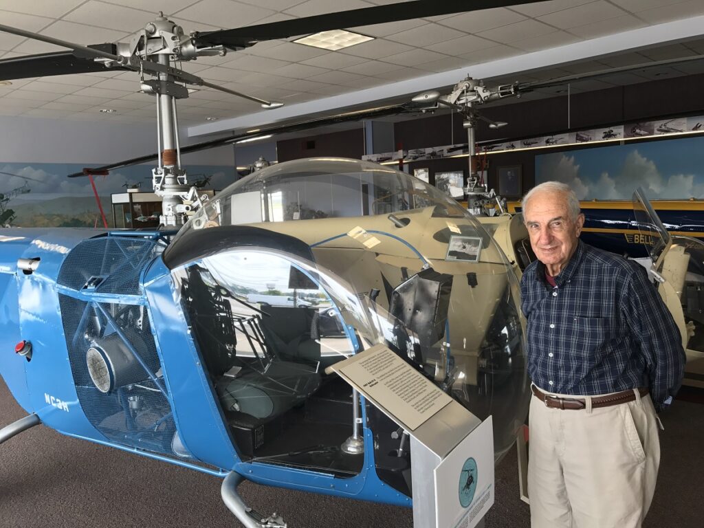 An image of Nelson Faso in front of the Bell 47 helicopter he worked on in high school and after retirement.